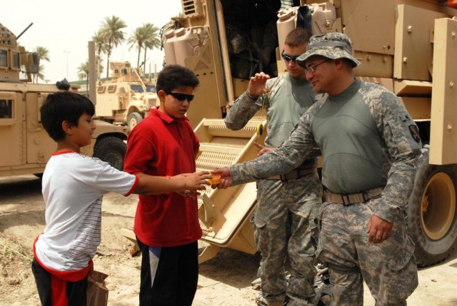 BAGHDAD - Staff Sgt. Adam Sanchez (right), of Alexandria, La., gives his yo-yo to Ali and his brother, Hamza, June 6, outside of Salam Palace in Baghdad. The 225th Engineer Brigade personnel security detachment members use yo-yo's to pass time....