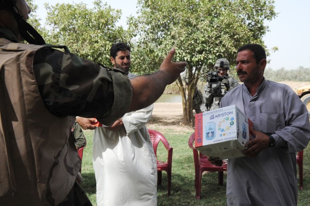 NAHIA WEHDA, Iraq - An Iraqi Army Soldier gives a resident of the Nahia Wehda region a water purification system during a combined foot patrol here, June 6. IA Soldiers partner with Paratroopers assigned to Company B, 1st Battalion, 505th...