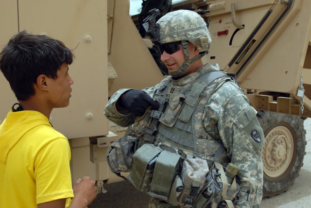 BAGHDAD - Capt. Christian Smith, commander Company A, 252nd Combined Arms Battalion, 30th Heavy Brigade Combat Team, chats with an Iraqi boy following a meeting with the al-Rashid District Advisory Council, here, June 9. Smith, a Morehead City,...