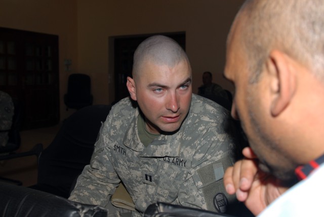 BAGHDAD - Capt. Christian Smith, commander of Company A, 252nd Combined Arms Battalion, 30th Heavy Brigade Combat Team, talks to an Iraqi man during a meeting of the al-Rashid District Advisory Council, June 9. Smith said the purpose of the...
