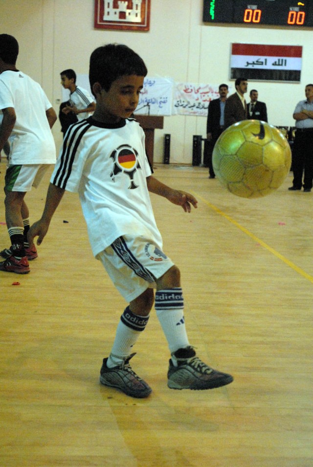 BAGHDAD, Iraq - A young boy from the soccer team kicks a soccer ball as his team shows off their skills. The al-Jazeera gymnasium opening, June 6, will not only help keep children off the streets, but will keep them indoors, supervised and safe, said...