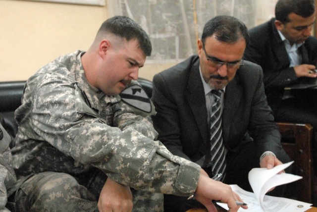 Newport News, Va., native, Capt. Jason Dudley (left), commander for Headquarters Company, 1st Battalion, 5th Cavalry Regiment, attached to the 1st Brigade Combat Team, 1st Cavalry Division, signs the Record of Return of Joint Security Station Suleikh...