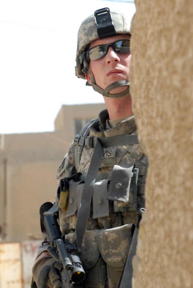 BAGHDAD - Walkertown, N.C., native, Spc. Justin Davis, an infantryman assigned to Company A, 252nd Combined Arms Battalion, 30th Heavy Brigade Combat Team, peers around a corner while searching for insurgents, weapons caches and explosives during...