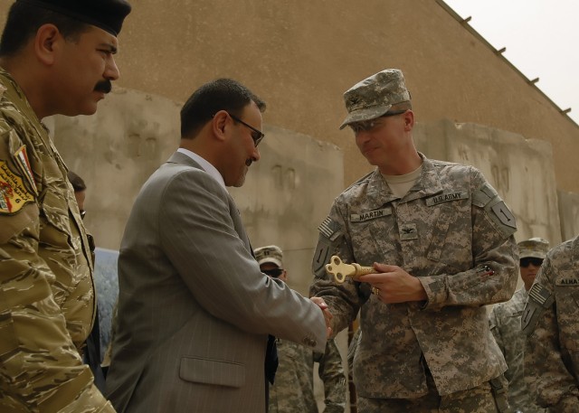 BAGHDAD - Col. Joseph Martin (right), a native of Dearborn, Mich., commander, 2nd Heavy Brigade Combat Team, 1st Infantry Division, Multi-National Division-Baghdad, hands a ceremonial key to Samir Haddad, a representative of the Office of the...