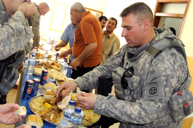 BAGHDAD - Staff Sgt. Richard Smith, of Tulsa, Okla., enjoys some Iraqi cuisine during the opening ceremony of a new civil support district center building June 11 in the city of Shawa Wa Um Jidir, located in the 9 Nissan District of eastern...