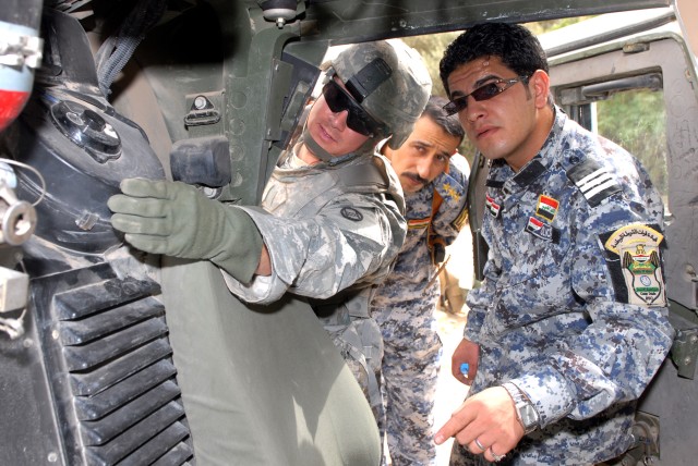 BAGHDAD - Sgt. Adam Mahaffey (left), an infantryman from North Wilkesboro, N.C., assigned to Company A, 252nd Combined Arms Battalion, 30th Heavy Brigade Combat Team, shows how to do basic humvee maintenance to Capt. Moaed Qasin Mohammed (center),...