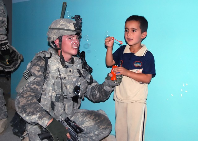 BAGHDAD - Spc. John Wayne Ringer, from Waynesburg, Pa, of Company B, 2nd Battalion, 112th Infantry Regiment "Paxton Rangers," 2nd Heavy Brigade Combat Team, 1st Infantry Division, teaches a child to blow bubbles at a youth center in the Abu Ghraib...