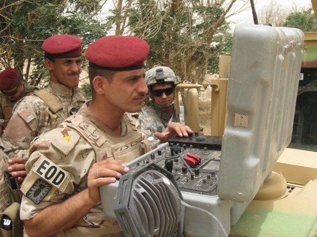 BAGHDAD- Pfc. Jamie Britton (back right), of Ontario, Ohio, an explosives ordnance detachment specialist assigned to the 1st Brigade Special Troops Battalion, 1st "Ironhorse" Brigade Combat Team, 1st Cavalry Division, supervises as Lt. Mohamed Arif, ...