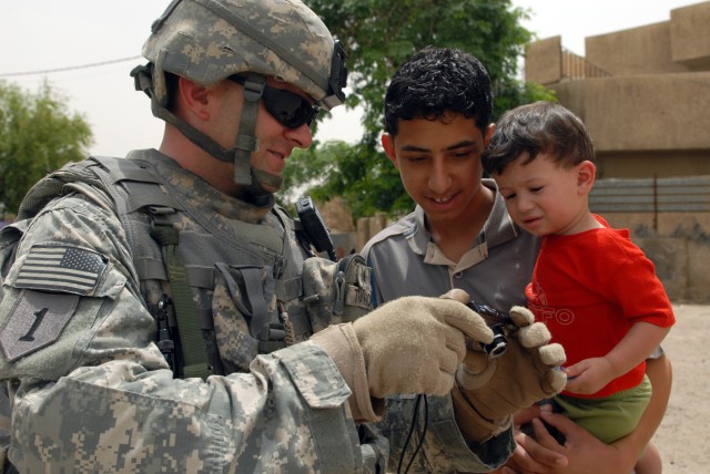 BAGHDAD - Sgt. Jason Traywick, a forward observer from Marshville, N.C., assigned to Company A, 252nd Combined Arms Battalion, 30th Heavy Brigade Combat Team, shows Iraqi children pictures he took of them with his digital camera in the Doura...