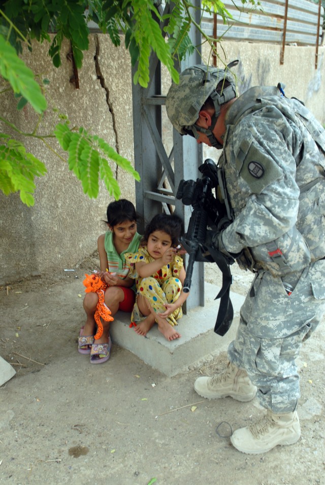 BAGHDAD - Sgt. John Beach of Roanoke Rapids, N.C., hands out candy to Iraqi children while on patrol in the Doura neighborhood, here, June 12. Beach is an infantryman assigned to Company A, 252nd Combined Arms Battalion, 30th Heavy Brigade Combat...