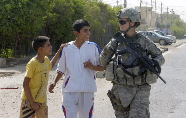 BAGHDAD - Pfc. Leigh Matchison, of Fort Thomas, Ky., talks to some Iraqi children during a foot patrol June 13 along a major highway in the 9 Nissan district of eastern Baghdad. Paratroopers assigned to the Military Police Platoon, Brigade Special Tr...