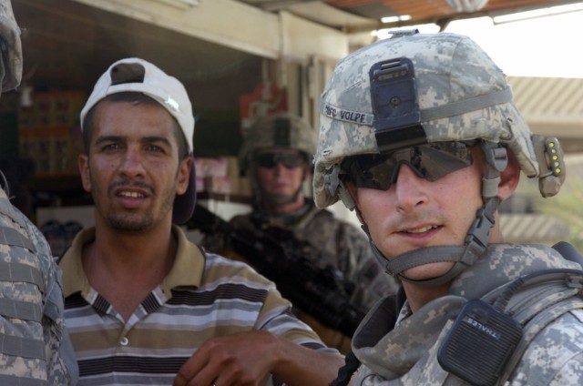 BAGHDAD - Sgt. 1st Class James Volpe, of Hopewell, N.J., talks to a local shop owner in order to assess security along a major eastern Baghdad highway during a foot patrol in the 9 Nissan district of eastern Baghdad, June 13. Volpe, a platoon sergean...