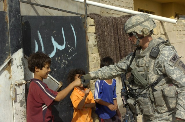 BAGHDAD - Sgt. 1st Class James Volpe, of Hopewell, N.J., gives some Iraqi children a fist pump greeting during a foot patrol June 13 along a major highway in the 9 Nissan district of eastern Baghdad. Volpe, a platoon sergeant with the Military Police...