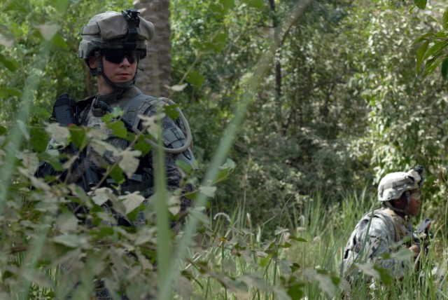 BAGHDAD - North Carolina National Guardsmen Spc. James Britt (left) of Pautego, N.C., and Spc. Juan Gonzalez (right) of Asheville, N.C., take a break while searching for weapons caches in a palm grove in Doura, here, June 13. Both Soldiers are...