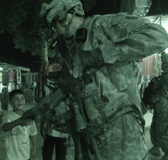 BAGHDAD - An Iraqi child shakes the hand of a Soldier of B Company, 252nd Combined Arms Battalion, 30th Heavy Brigade Combat Team, during a night patrol in the Saydiyah district of southern Baghdad, June 8, with Soldiers of the Iraqi Army. ...