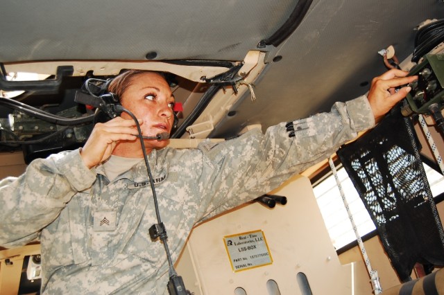 BAGHDAD - Sgt. Frankie Hibberd, a signal specialist with Company D, 230th Brigade Support Battalion, 30th Heavy Brigade Combat Team, checks the frequency and volume of radio headsets before an early morning convoy, June 11. The Charleston, W. Va. nat...