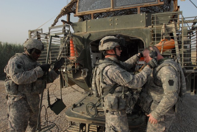NUBAI, Iraq - Staff Sgt. Joshua Bentley (center), of York, Pa. helps Pfc. Harry Gill of Doylestown, Pa. put on a set of headphones used to operate a metal detector as Pfc. Darryl Strickland of Philadelphia readies his metal detector June 16 near...