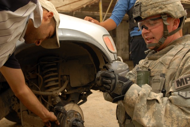 BAGHDAD - Staff Sgt. Preston O'Neal, a military policeman assigned to 463rd Military Police Company, 93rd Military Police Battalion, 8th Military Police Brigade, takes time to use his mechanical skills to help an Iraqi identify a problem with the...