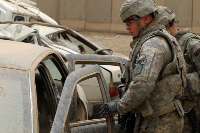 BAGHDAD - Cpl. Jonathan Montgomery (left) of Tyler, Texas, and Pfc. Kyle Crossley of Queen Creek, Ariz., search an abandoned car while on patrol with the IP in the Ameriyah neighborhood, here, June 17. Montgomery and Crossley, both military...