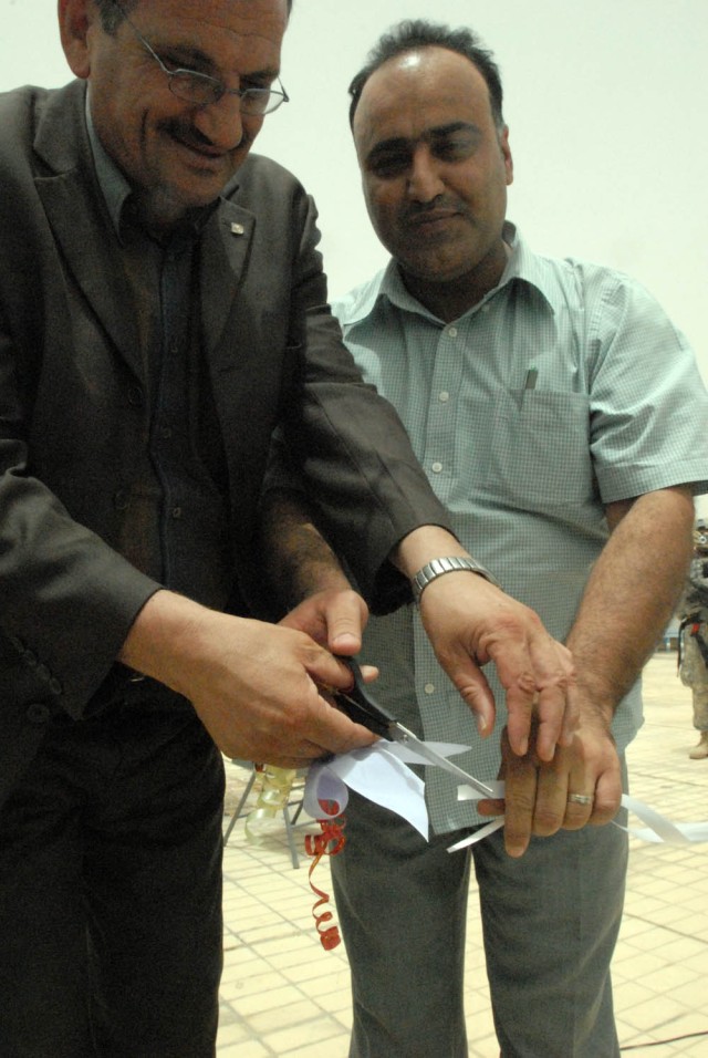 BAGHDAD, Iraq - Mr. Hadi Hasan, the Qaim Maqam (left) and the District Advisory Council chairman cut the rope at the grand opening ceremony of the Sha'ab pool on June 17. Ali Muften (right) stated that he hopes that the neighborhood children will...