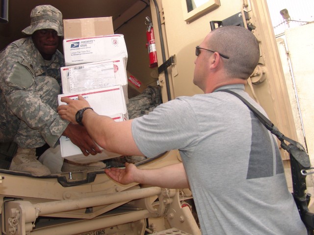 BAGHDAD - Spc. Naquian McDaniel (left), of Princeton, N.C., hands Spc. Sonny Fleeman, of McLeansville, N.C., care packages for Soldiers of B Company, 252nd Combined Arms Battalion, 30th Heavy Brigade Combat Team, at Joint Security Station Saydiyah...