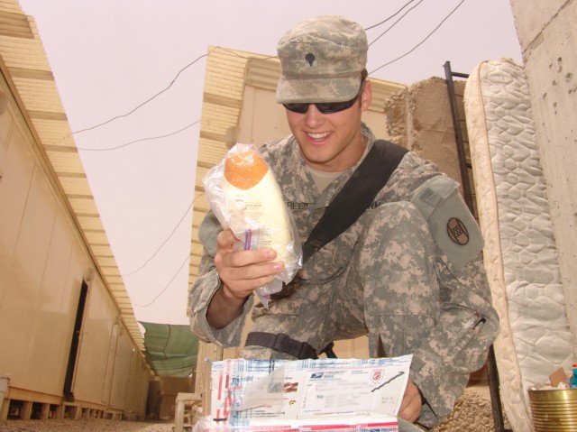 BAGHDAD - Spc. Mark Green, an infantryman with B  Company, 252nd Combined Arms Battalion, 30th Heavy Brigade Combat Team, from Smithfield, N.C., smiles as he discovers the contents of a care package from delivered to Soldiers at Joint Security...