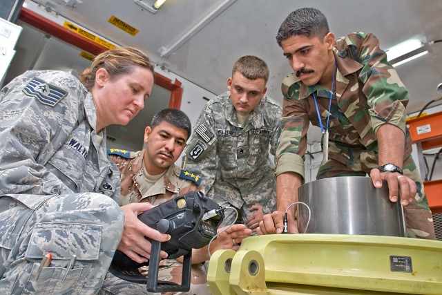 CAMP TAJI, Iraq-1st Lt. Abbas (second from left) of the Iraqi Air Force, Tech. Sgt. Andrea Walton (left), a non-destructive inspection air advisor for the Coalition Air Force Training Team, 721st Air Expeditionary Advisor Squadron, and Sgt. Kenneth W...