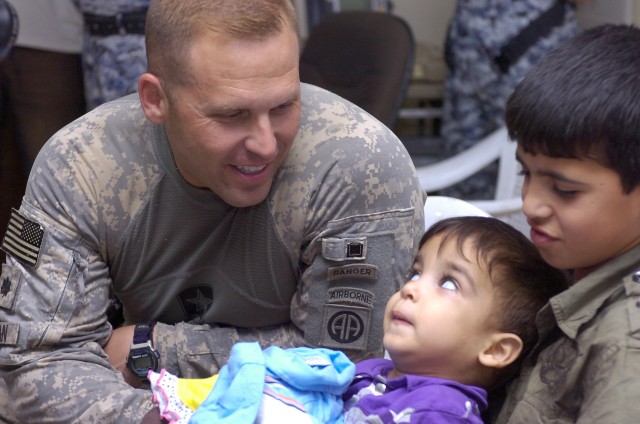 BAGHDAD - Lt. Col. Louis Zeisman, of Fayetteville, N.C., greets a handicapped Iraqi boy during a humanitarian event, June 20, at Joint Security Station Beladiyat, located in the 9 Nissan district of eastern Baghdad. Paratroopers assigned to the 2nd B...