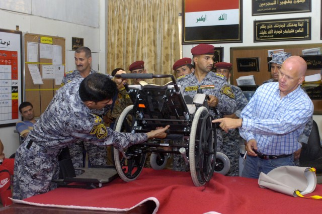 BAGHDAD - Brad Blauser (right), of Dallas, Texas, founder of Wheelchairs for Iraqi Kids, along with Iraq Brig. Gen. Ali Ibraheem Dabown, show parents of handicapped children how to adjust the wheelchairs they are about to receive during a humanitaria...