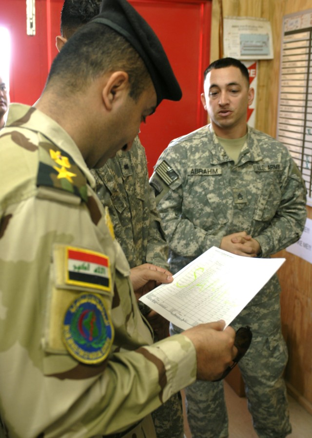 BAGHDAD - Staff Sgt. Jason Abrahim (right), brigade medical supply office noncommissioned officer in charge, shows Lt. Col. Mortadha Jafar Mosa, 6th Iraqi Army Division surgeon, an example of an Army document used to order medical supplies, June 19, ...