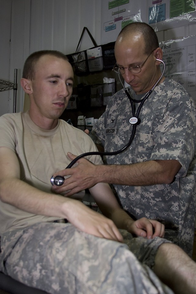 CAMP TAJI, Iraq-Col. Stephen Burnstein, from Enterprise, Ala., director of aviation medicine, attached to the 1st Air Cavalry Brigade, 1st Cavalry Division, Multi-National Division - Baghdad, conducts an examination on Pvt. Robert Warner, from Pocatt...