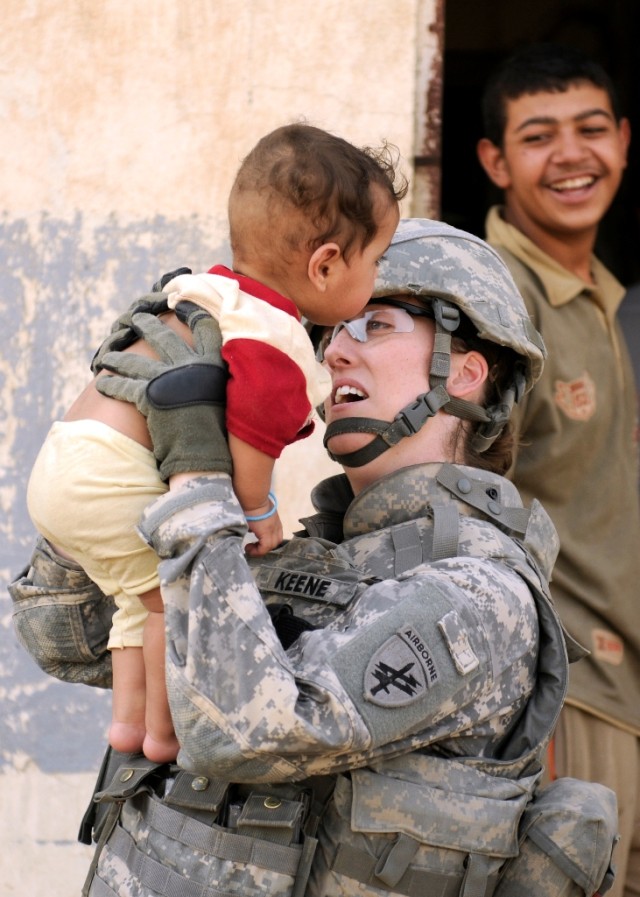 BAGHDAD - Sgt. Elisabeth Keene, attached to the 120th Combined Arms Battalion, 30th Heavy Brigade Combat Team, plays with a little boy outside of Forward Operating Base Mahmudiyah, June 22. Keene, of Fairfax, Va., is part of a group of Soldiers who w...
