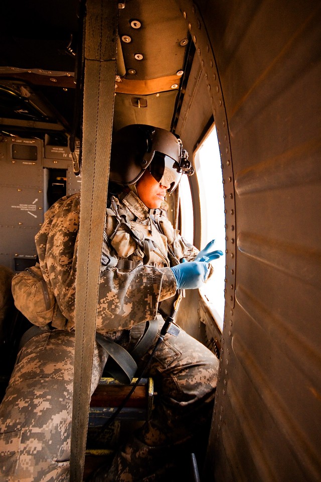 TAJI, Iraq-Watching vigilantly out of the window for the landing site, Sgt. Karen Henson, from Fredericksburg, Va., a flight medic in Company C "Medevac," 2nd Battalion, 1st Air Cavarly Brigade, 1st Cavarly Division, puts on her surgical gloves as...