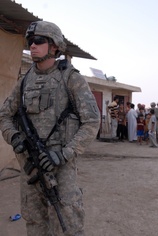 BAGHDAD - Sgt. Eric Engstrom, a tanker from Becket, Mass., assigned to Company D, 1st Battalion, 63rd Combined Arms Battalion, 2nd Brigade Combat Team, 1st Infantry Division, pulls security duty while his fellow Soldiers distribute pamphlets advertis...