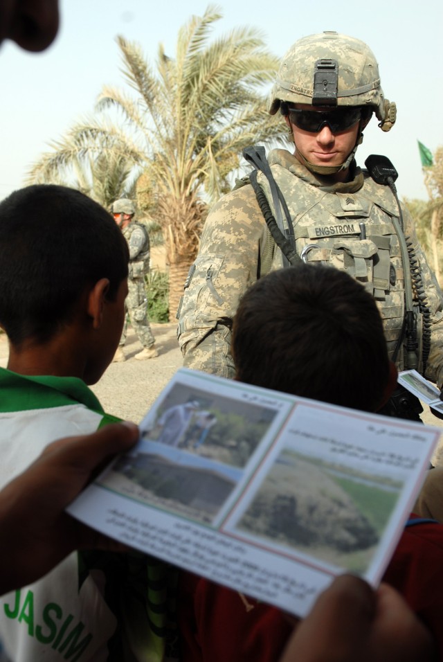 BAGHDAD - An Iraqi man reads a pamphlet handed out by Sgt. Eric Engstrom during a patrol of the Khadir village in the Abu Ghuraib area, here, June 22. Engstrom, a tanker from Becket, Mass., is assigned to Company D, 1st Battalion, 63rd Combined Arms ...