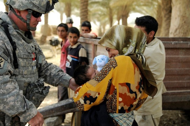 090623-A-8124P-015
MAHMUDIYAH, Iraq - Sgt.Kenneth Steinbronn, 120th Combined Arms Battalion, 30th Heavy Brigade Combat Team, hands a stuffed toy to an infant at a dairy farm near Mahmudiyah, June 23.  Steinbronn, of Dorchester, N.C., and other member...