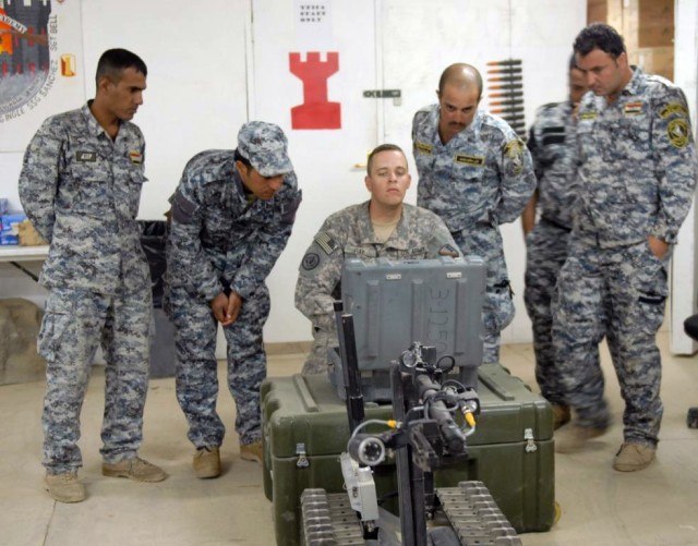 BAGHDAD - Staff Sgt. Joseph Ray (center), of Baton Rouge, La., gives instruction to Iraqi 2nd NP officers on how to maneuver the Talon robot, used to detect deadly IEDs. The class was part of a three-day course on route clearance taught at the...
