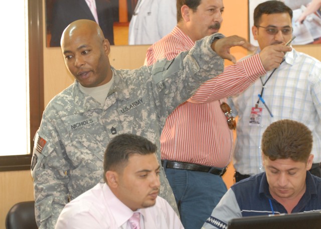 Sgt. 1st Class Marvin Nichols, 56th Stryker Brigade Combat Team's senior geospatial intelligence engineer, shows Iraqi Ministry of Water and Ministry of Agriculture technicians features of a mapping program, June 21, during a conference in the...