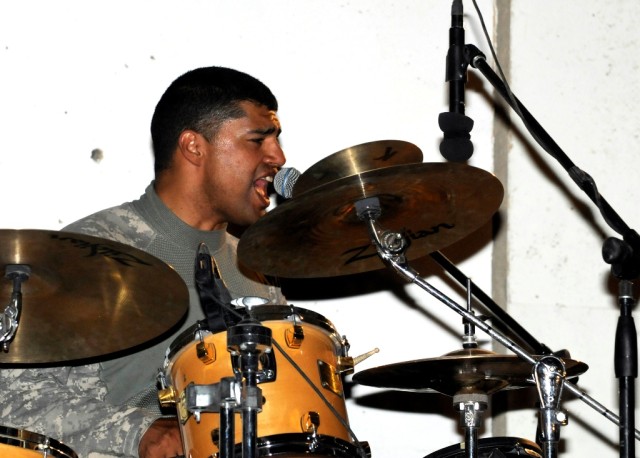 MAHMUDIYAH, Iraq - Drummer Staff Sgt. Rudy Rendon, of Uvalde, Texas, of the 1st Calvary Division Army Rock Band, sings during their show at Forward Operating Base Mahmudiyah, June 23. The band, known as G.O. 1 Underground, plays for Soldiers in...