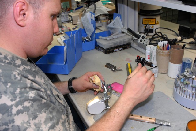 BAGHDAD - Sgt. David Dickinson, who hails from Salt Lake City, assigned to the 464th Medical Company (DS), 421st Multifunctional Medical Battalion, 44th Medical Command, Multi-National Division-Baghdad, heats up a tool that gathers and molds wax to h...