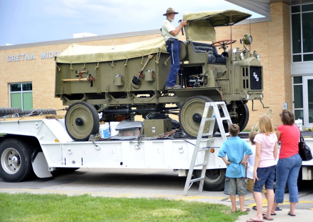 Don Chew, Brighton, Colo., talks to a group of visitors while making repairs to a canvas tarp on his 1917 Four Wheel Drive truck in the Gretna Middle School Parking lot, June 24. Chew is a member of the Military Vehicle Preservation Association...