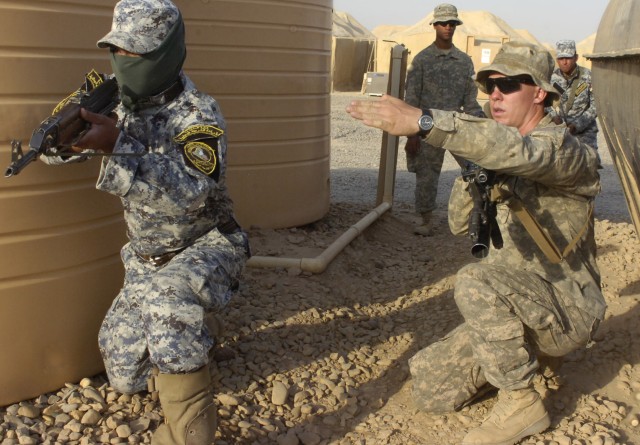 Pvt. Nicholas Culpepper, of Raleigh, N.C., advises a National Police officer assigned to the 3rd NP Brigade, 1st NP Division to point his weapon toward a certain direction in order to provide security for his fellow officers who are entering and clea...