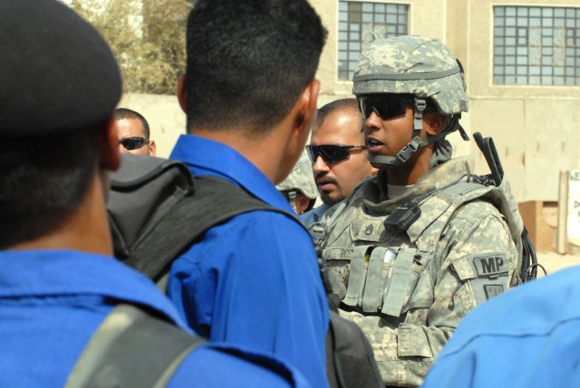 BAGHDAD - Staff Sgt. Maurice Rice (right), a squad leader from Chicago, assigned to the 463rd Military Police Company, 93rd Military Police Battalion, 8th Military Police Brigade, speaks with the Iraqi police of al-Mansour about maintaining police...