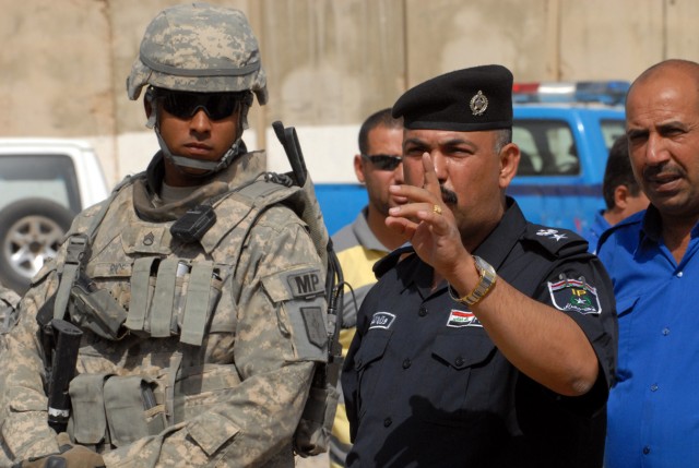 BAGHDAD - Staff Sgt. Maurice Rice (left), a squad leader from Chicago, assigned to the 463rd Military Police Company, 93rd Military Police Battalion, 8th Military Police Brigade, watches as Lt. Col. Abbas instructs police during guard mount in...