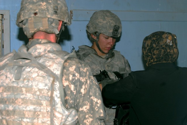 BAGHDAD - Spc. Erika Downey, a Cape Coral, Fla. native, a military police officer assigned to the 463rd Military Police Company, 93rd Military Police Battalion, 8th Military Police Brigade, searches an Iraqi woman as she enters the police station...