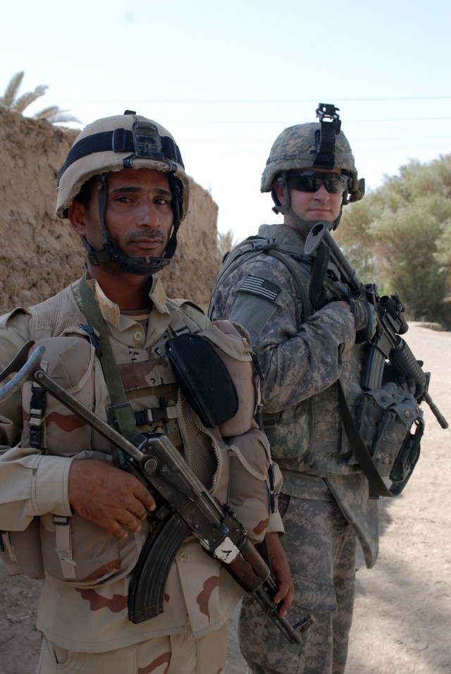 BAGHDAD - Spc. Jon Morris of Lakewood, Ohio, a medic assigned to Company A, 1st Combined Arms Battalion, 63rd Armored Regiment, 2nd Brigade Combat Team, 1st Infantry Division, stands with an Iraqi soldier during a joint combat patrol of...