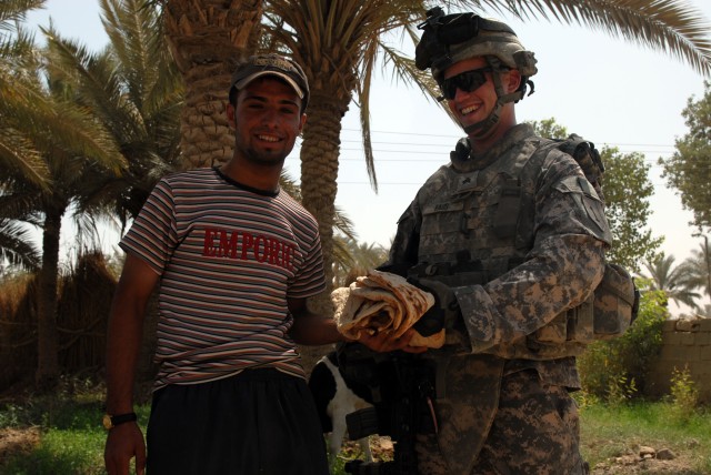 BAGHDAD - Sgt. Brandt Faus accepts homemade bread from an Iraqi man in the village of al-Fallujean in the Abu Ghraib area here, June 24. Faus, an infantryman assigned to Company A, 1st Combined Arms Battalion, 63rd Armored Regiment, 2nd Brigade...
