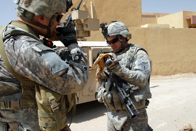 BAGHDAD - Staff Sgt. Ramon Esparaza-Reyes (left) of Yuma, Ariz., and Spc. Michael Thornton of Dallas share a piece of bread given to them by an Iraqi man in the village of al-Fallujean in the Abu Ghraib area here, June 24. Both Soldiers are...