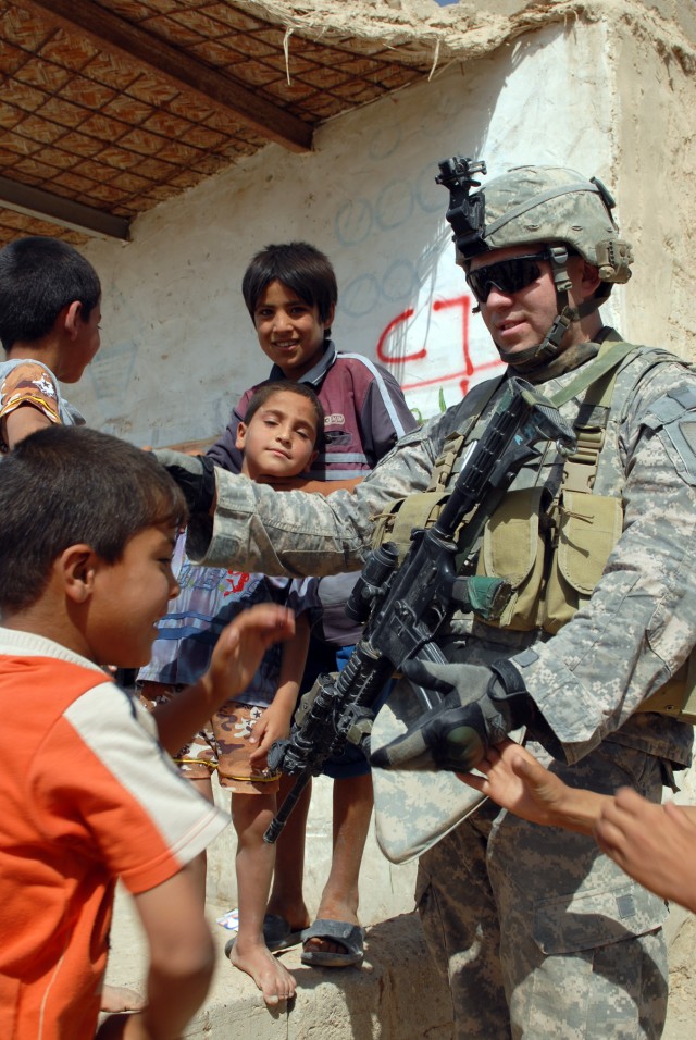 BAGHDAD - Staff Sgt. Ramon Esparaza-Reyes of Yuma, Ariz. greets Iraqi children during a patrol of the village of al-Fallujean in the Abu Ghraib area here, June 24. Esparaza is an infantryman assigned to Company A, 1st Combined Arms Battalion, 63rd...