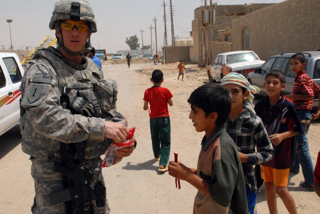 BAGHDAD - 1st Lt. Justin Casey, from Ogdensburg, N.Y., assigned to the Joint Projects Management Office, 2nd Brigade, 1st Infantry Division, hands out candy to Iraqi children in the Nasir Wa Salam neighborhood here, June 25. Children seemed to...